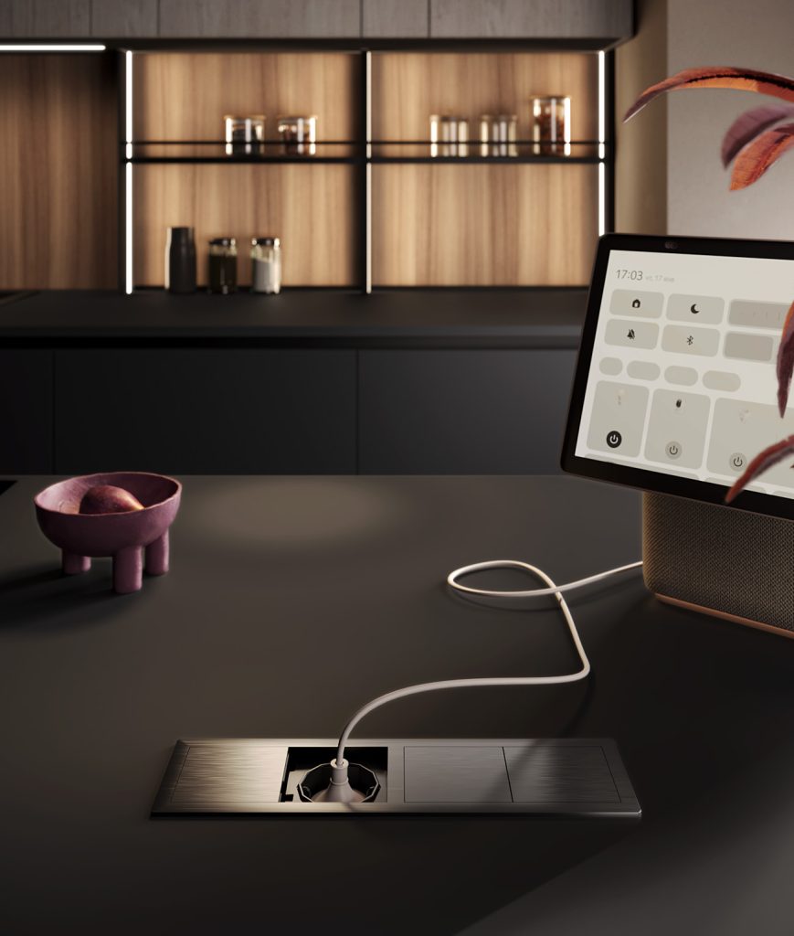 Dettaglio della presa a scomparsa nel piano e tablet domotico della cucina Modern & Design Ginevra di Ciao Cucine, ambiente effetto legno chiaro